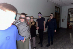 Bērni spēlē spēli skolas koridorā ar aizsietām acīm