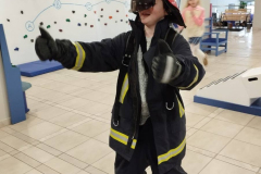 Priecīgs bērns ugunsdzēsēja uniformā.