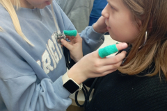 Divas meitenes klausās vien otrai sirdi izmantojot stetoskopu