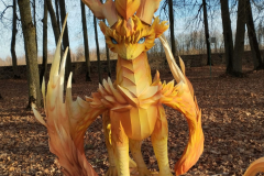 Bilde parkā parādot bērnešķīga dizaina ugunīgu krāsu pūķa statuju.