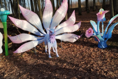 Bilde parkā parādot zilgan-rozu lapsas statuju ar deviņām astēm.