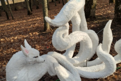 Bilde parkā parādot baltu lapsas statuju ar daudzām astēm.
