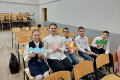 Skolēni sēž krēslos ar izgrieztām konfektēm
