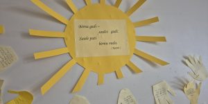 Izgriezta saulīte pielīmēta pie sienas ar tekstu "Bērna gadi - saules gadi: Saule pati bērnu vada. (Rainis)"