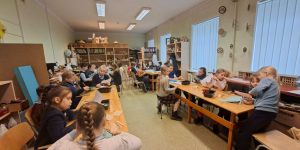 Bērni apstrādāt papīru pie galdiem darbnīcā