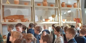 Bērni Daugavpils Vienības nama Tradīciju mājā skatās māla trauku ekspozīciju