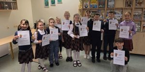 Skolēnu kopbilde ar doplomiem skolas bibliotēkā