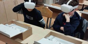 Divi bērni ar uzvilktām VR brillēm sēž pie galda