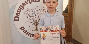 2.b klases skolnieks stāv ar savu diplomu