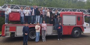 4.a klase stāv pie un uz ugunsdzēsēju auto