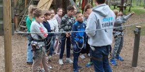 Skolēni klausās instruktoru pirms aktivitāšu sākuma meža takā